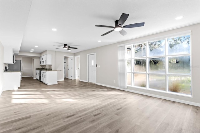 unfurnished living room featuring ceiling fan and light wood-type flooring