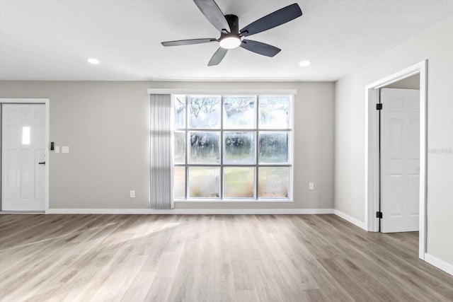 unfurnished living room with ceiling fan, a textured ceiling, and light wood-type flooring