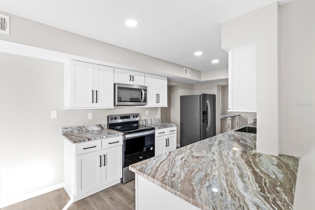 kitchen featuring white cabinetry, sink, light hardwood / wood-style floors, stainless steel appliances, and light stone countertops