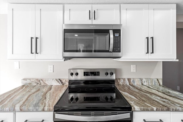 kitchen with white cabinetry, appliances with stainless steel finishes, and dark stone countertops