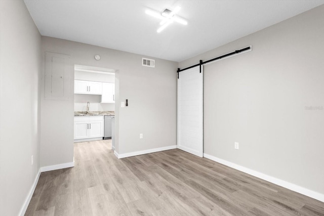 spare room with a barn door, sink, and light hardwood / wood-style floors