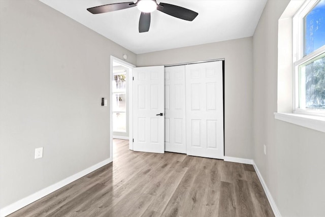 unfurnished bedroom featuring ceiling fan, a closet, and light wood-type flooring