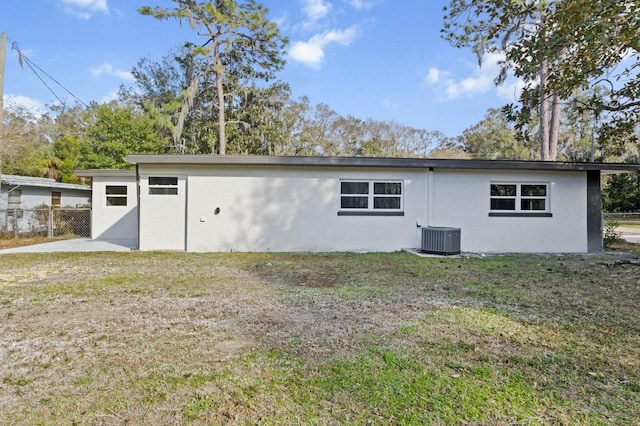 rear view of house with central AC and a lawn