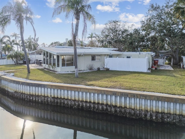 back of property featuring a sunroom and a lawn