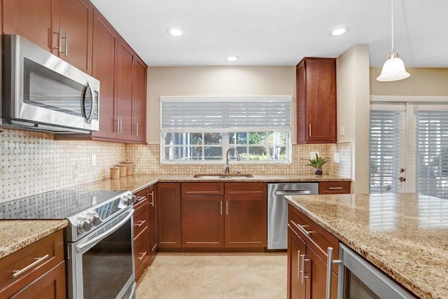 kitchen with decorative light fixtures, sink, backsplash, light stone counters, and stainless steel appliances