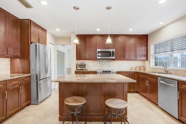 kitchen with pendant lighting, sink, a breakfast bar area, appliances with stainless steel finishes, and a kitchen island