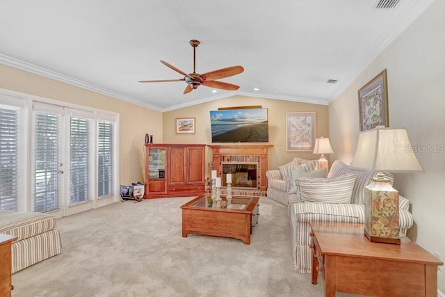 living room with lofted ceiling, ceiling fan, a fireplace, ornamental molding, and light colored carpet