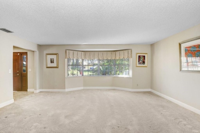 carpeted empty room featuring a textured ceiling