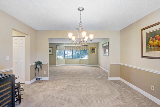 unfurnished dining area featuring an inviting chandelier, light colored carpet, and a textured ceiling