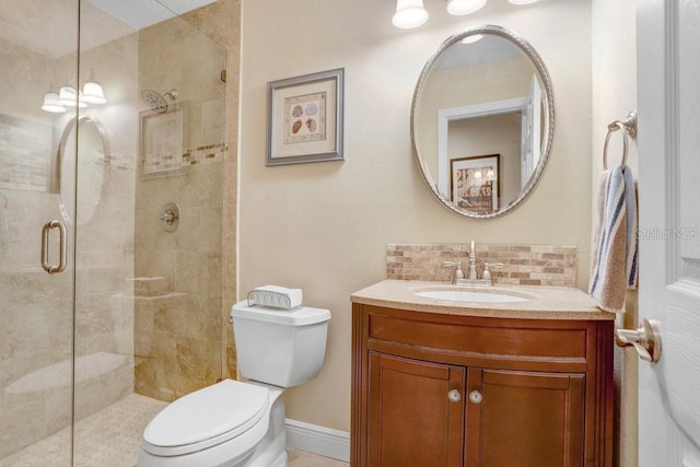 bathroom with vanity, toilet, a shower with door, and backsplash