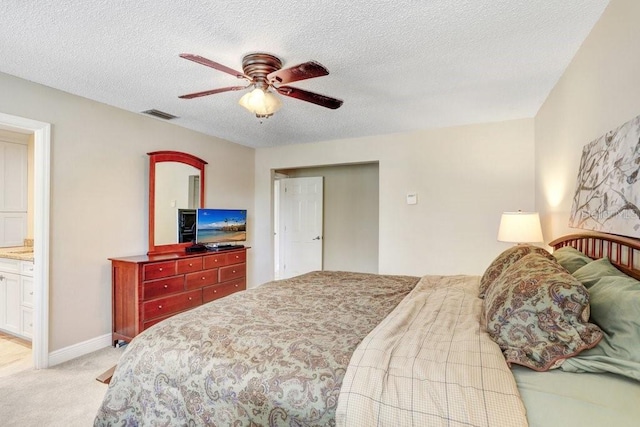 bedroom featuring ceiling fan, light colored carpet, connected bathroom, and a textured ceiling