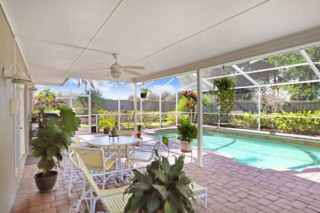 view of swimming pool with ceiling fan, a patio area, and glass enclosure