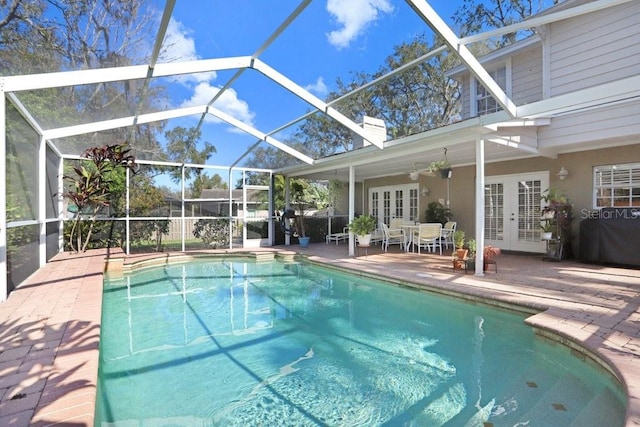 view of swimming pool with a patio, ceiling fan, glass enclosure, and french doors