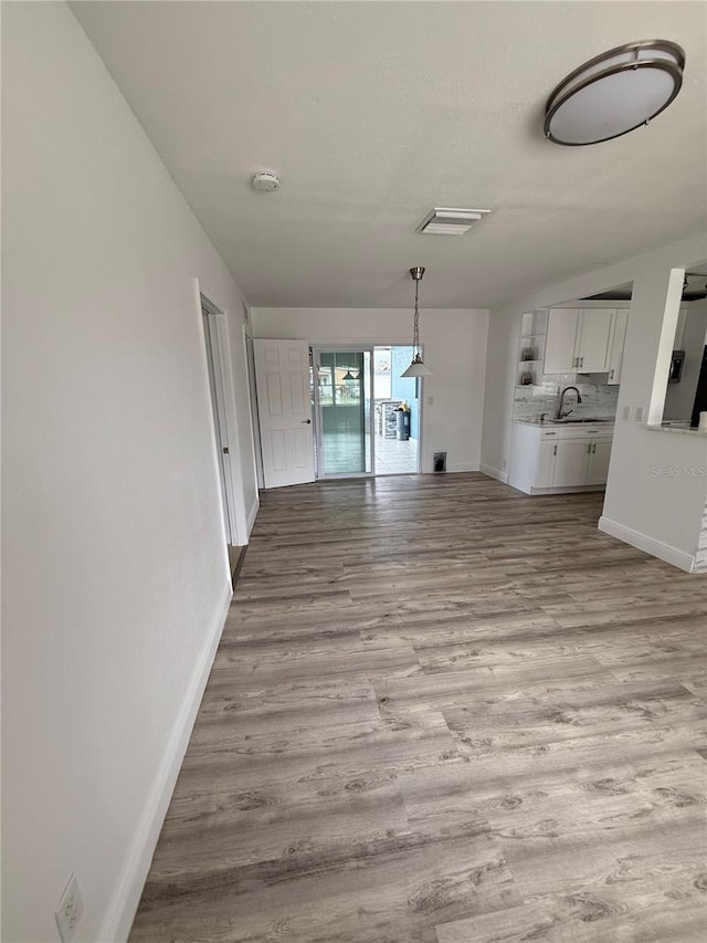 unfurnished living room with sink, light hardwood / wood-style flooring, and a textured ceiling