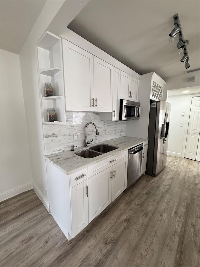 kitchen with sink, white cabinetry, light stone counters, hardwood / wood-style flooring, and stainless steel appliances