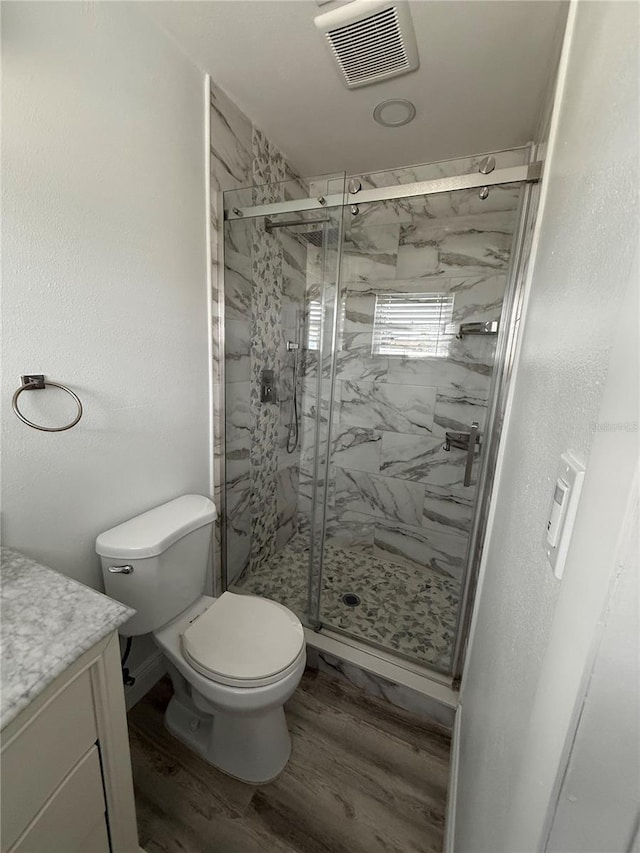 bathroom featuring hardwood / wood-style flooring, vanity, toilet, and an enclosed shower