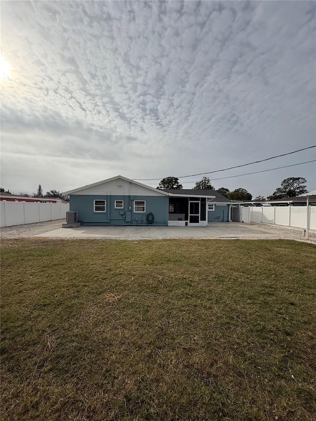 view of front of property featuring a front lawn, central air condition unit, and a patio area