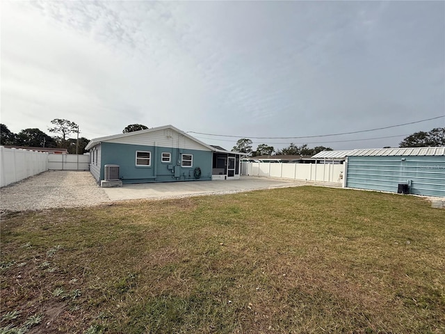 back of property with central AC unit, a patio, and a lawn