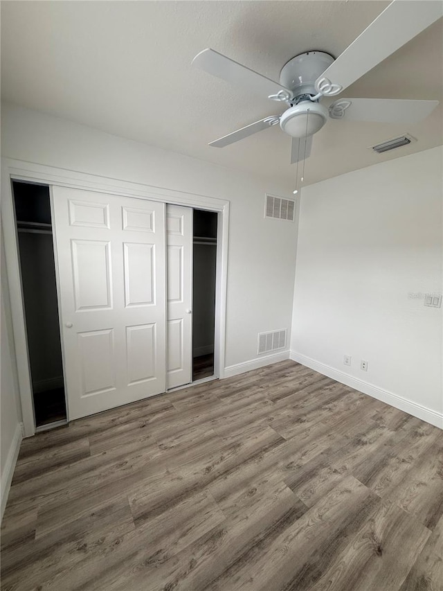 unfurnished bedroom with hardwood / wood-style floors, a closet, and ceiling fan