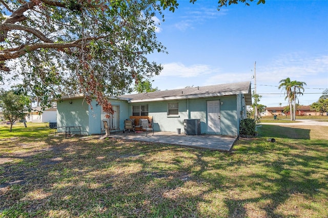 rear view of house with cooling unit, a patio area, and a lawn