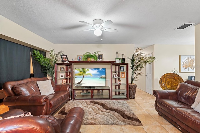 living room featuring light tile patterned flooring, ceiling fan, and a textured ceiling