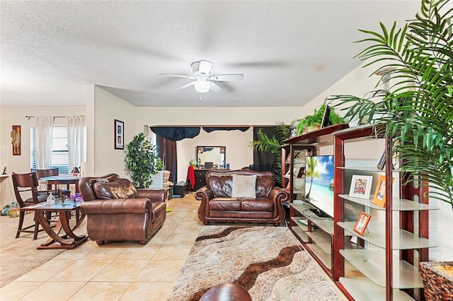 living room with light tile patterned flooring, ceiling fan, and a textured ceiling