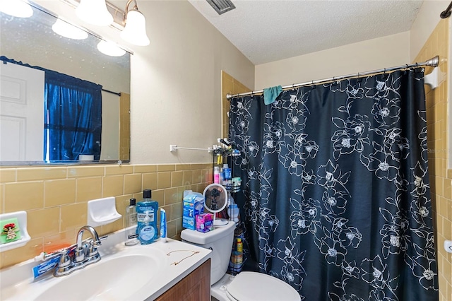 bathroom featuring tile walls, vanity, a textured ceiling, toilet, and walk in shower