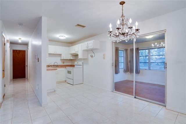 kitchen featuring white electric stove, hanging light fixtures, sink, and white cabinets