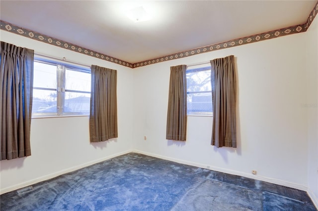 unfurnished room featuring dark carpet