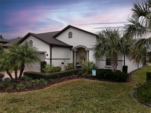 mediterranean / spanish house featuring stucco siding, a front lawn, and a garage