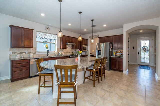4748 Ballast Crest Cv, Land O Lakes, FL 34638 - kitchen with appliances with stainless steel finishes, arched walkways, backsplash, a breakfast bar area, and a kitchen island
