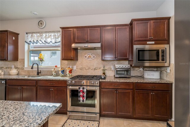 4748 Ballast Crest Cv, Land O Lakes, FL 34638 - kitchen featuring appliances with stainless steel finishes, under cabinet range hood, light stone countertops, a sink, and backsplash