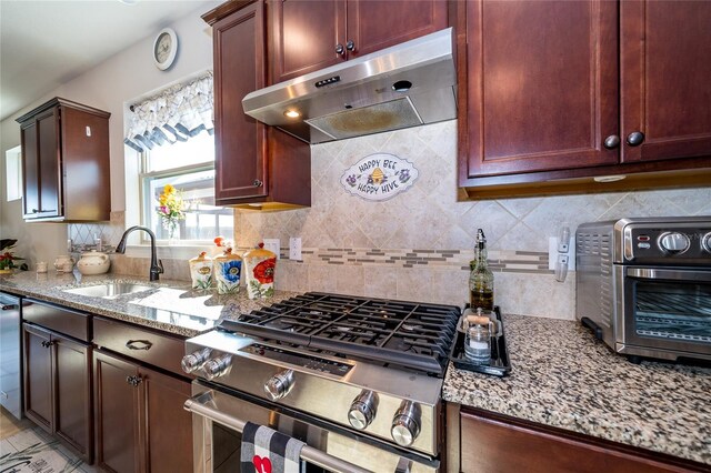 4748 Ballast Crest Cv, Land O Lakes, FL 34638 - kitchen with under cabinet range hood, stainless steel appliances, a sink, light stone countertops, and tasteful backsplash
