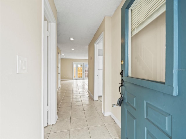 corridor with light tile patterned floors, a textured ceiling, and french doors