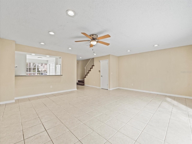 unfurnished room with ceiling fan, light tile patterned floors, and a textured ceiling