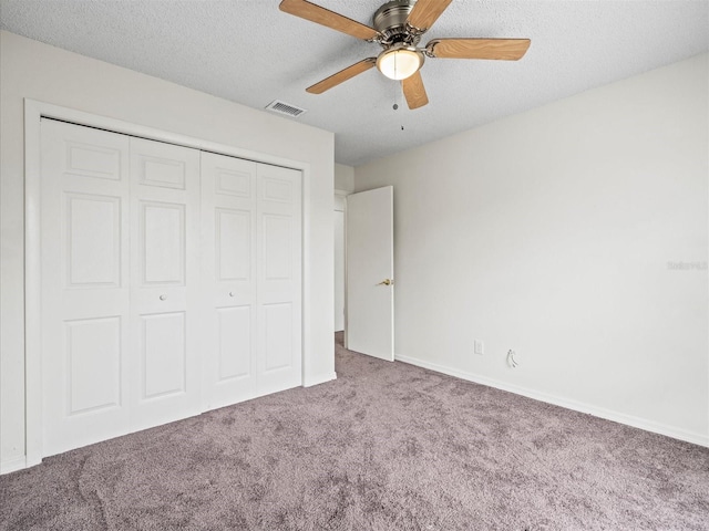 unfurnished bedroom with ceiling fan, carpet, a textured ceiling, and a closet