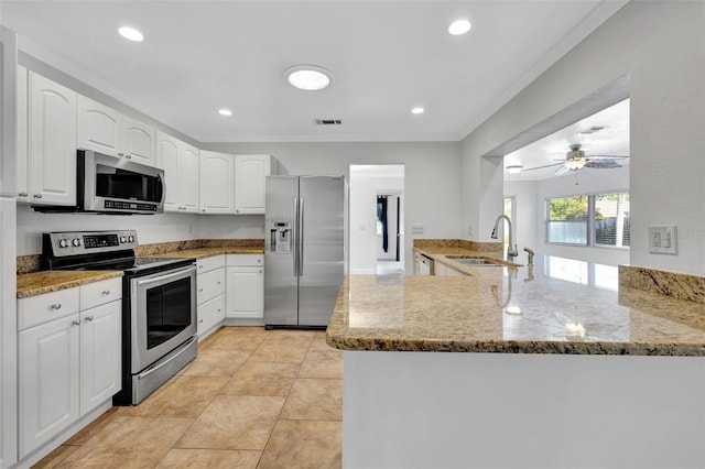 kitchen featuring sink, appliances with stainless steel finishes, light stone countertops, white cabinets, and kitchen peninsula