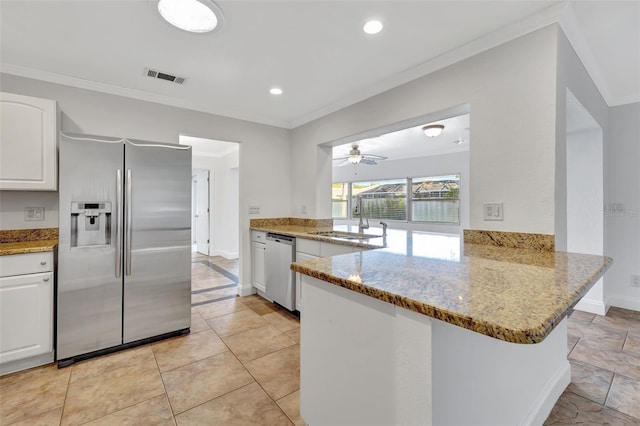 kitchen with sink, white cabinetry, light stone counters, appliances with stainless steel finishes, and kitchen peninsula