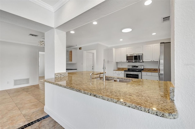 kitchen with sink, white cabinetry, light stone counters, appliances with stainless steel finishes, and kitchen peninsula