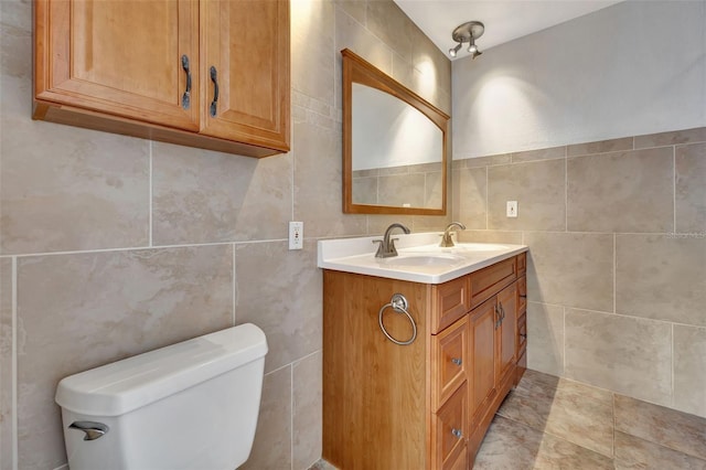 bathroom with tile patterned floors, vanity, toilet, and tile walls