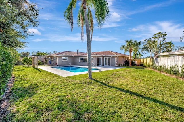 back of house featuring a yard, a fenced in pool, and a patio area