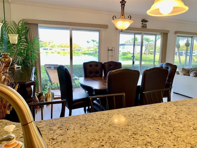 dining room featuring a water view, tile patterned floors, and crown molding