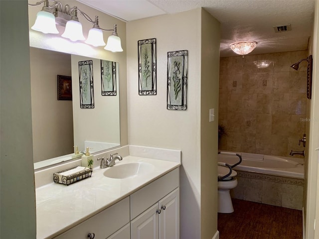 full bath featuring tiled shower / bath, visible vents, a textured ceiling, and vanity