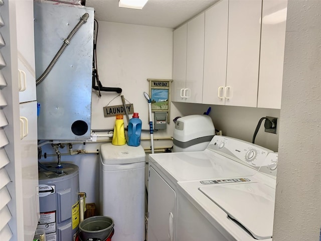 laundry room featuring washing machine and dryer, cabinet space, and water heater