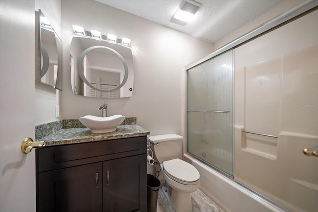 full bathroom with bath / shower combo with glass door, vanity, a textured ceiling, and toilet