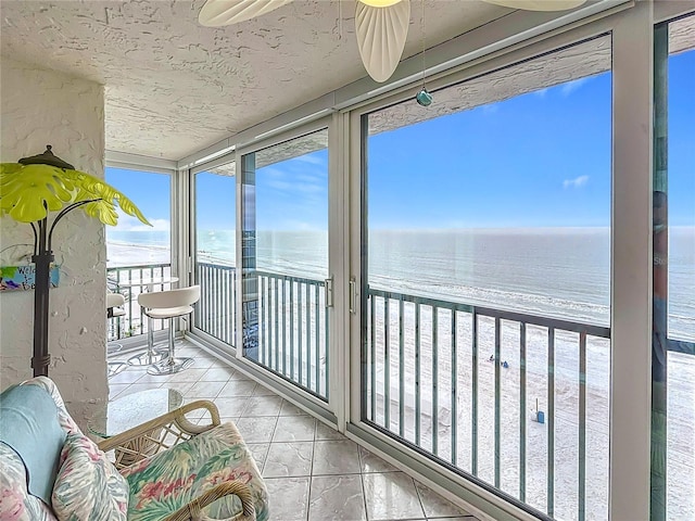 sunroom / solarium featuring a water view and a view of the beach