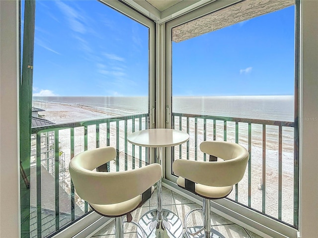 balcony with a water view and a view of the beach