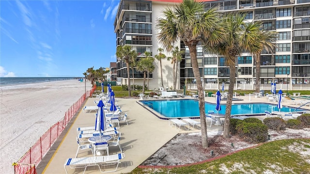 view of pool featuring a view of the beach, a patio area, and a water view