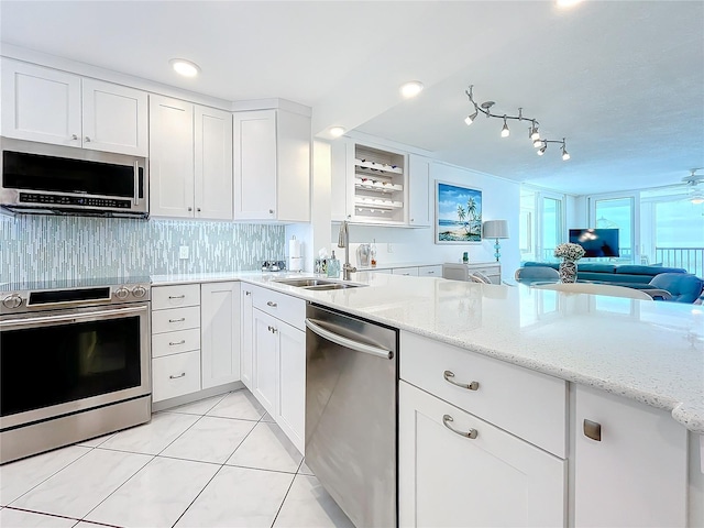 kitchen featuring sink, appliances with stainless steel finishes, light stone counters, white cabinets, and light tile patterned flooring