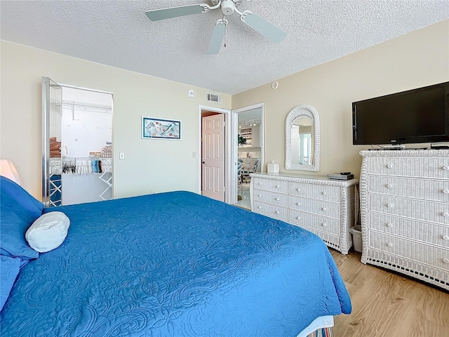 bedroom featuring ceiling fan, light hardwood / wood-style flooring, and a textured ceiling